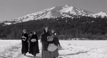 Movie still from “Day of the Outlaw” (1959), directed by André De Toth – A black and white photo of a group of people walking through the snow; Wide shot, Low angle