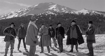 Movie still from “Day of the Outlaw” (1959), directed by André De Toth – A black and white photo of a group of men standing in the snow; Wide shot, High angle