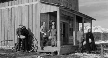 Movie still from “Day of the Outlaw” (1959), directed by André De Toth – A black and white photo of men standing in front of a building; Wide shot, Low angle