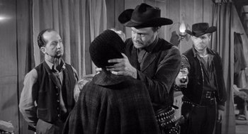 Movie still from “Day of the Outlaw” (1959), directed by André De Toth – A man in a cowboy hat is putting a hat on a woman's head; Medium shot, Over the shoulder angle