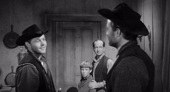 Movie still from “Day of the Outlaw” (1959), directed by André De Toth – A group of men standing next to each other in front of a door; Medium shot, Over the shoulder angle