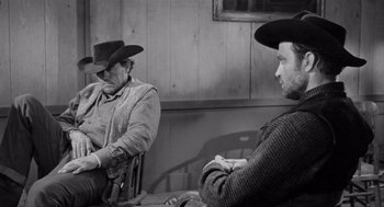 Movie still from “Day of the Outlaw” (1959), directed by André De Toth – Two men sitting in chairs wearing cowboy hats; Medium shot, Over the shoulder angle