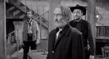 Movie still from “Day of the Outlaw” (1959), directed by André De Toth – A black - and - white photo of a man and two other men; Medium shot, Over the shoulder angle