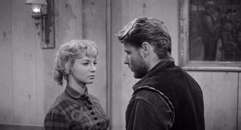Movie still from “Day of the Outlaw” (1959), directed by André De Toth – A man and a woman standing next to each other in front of a wall; Close Up shot, Over the shoulder angle