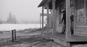 Movie still from “Day of the Outlaw” (1959), directed by André De Toth – An old photo of a man standing on the porch of a house; Wide shot, Low angle