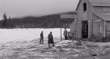 Movie still from “Day of the Outlaw” (1959), directed by André De Toth – A group of men standing next to a wooden building; Wide shot, Low angle
