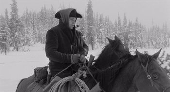 Movie still from “Day of the Outlaw” (1959), directed by André De Toth – A man on a horse in the snow with trees in the background; Medium shot, Low angle
