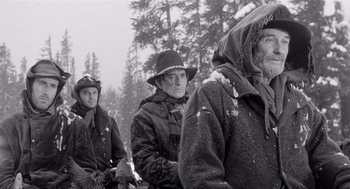 Movie still from “Day of the Outlaw” (1959), directed by André De Toth – A group of men sitting on top of a snow covered slope; Medium shot, Low angle
