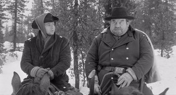 Movie still from “Day of the Outlaw” (1959), directed by André De Toth – Two men sitting in the snow next to a tree; Medium shot, Low angle