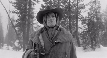 Movie still from “Day of the Outlaw” (1959), directed by André De Toth – An old photo of a man holding a gun in the snow; Medium shot, Low angle
