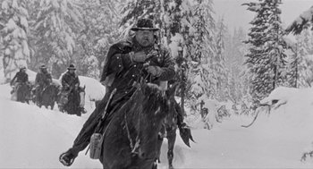 Movie still from “Day of the Outlaw” (1959), directed by André De Toth – A man riding a horse through the snow; Wide shot, Low angle