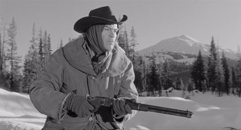 Movie still from “Day of the Outlaw” (1959), directed by André De Toth – A man in a cowboy hat holding a rifle; Medium shot, Low angle