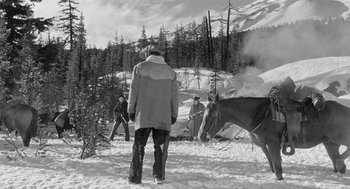 Movie still from “Day of the Outlaw” (1959), directed by André De Toth – A group of people standing in the snow near horses; Wide shot, High angle