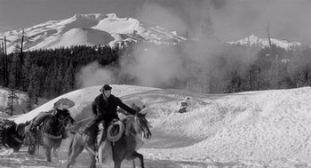 Movie still from “Day of the Outlaw” (1959), directed by André De Toth – A man riding on the back of a horse in the snow; Wide shot, High angle