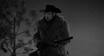 Movie still from “Day of the Outlaw” (1959), directed by André De Toth – A man holding a gun while wearing a hat; Medium shot, Low angle