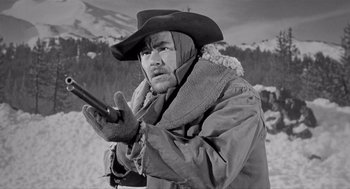 Movie still from “Day of the Outlaw” (1959), directed by André De Toth – A man wearing a hat and holding a gun in his hand; Medium shot, Low angle