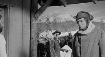 Movie still from “Day of the Outlaw” (1959), directed by André De Toth – A man standing next to a horse in front of some trees; Medium shot, Low angle