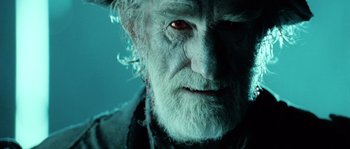 Movie still from “Daybreakers” (2009), directed by Michael Spierig – An old man with a beard and a red eye; Close Up shot, Over the shoulder angle