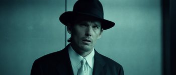 Movie still from “Daybreakers” (2009), directed by Michael Spierig – A man in a suit and hat is looking at the camera; Close Up shot, Low angle