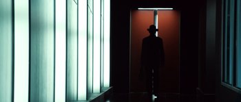 Movie still from “Daybreakers” (2009), directed by Michael Spierig – A man wearing a hat is standing in front of a window; Wide shot, Low angle