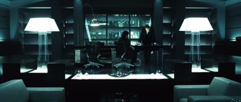 Movie still from “Daybreakers” (2009), directed by Michael Spierig – Two people sitting at a desk in a dark room; Wide shot, High angle