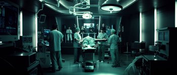 Movie still from “Daybreakers” (2009), directed by Michael Spierig – A group of people standing around a patient in an operating room; Wide shot, High angle