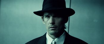 Movie still from “Daybreakers” (2009), directed by Michael Spierig – A man wearing a suit and a hat; Close Up shot, Over the shoulder angle