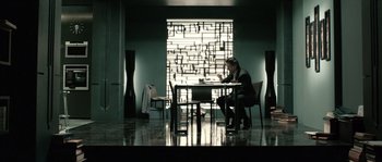 Movie still from “Daybreakers” (2009), directed by Michael Spierig – A person sitting at a table in a room; Wide shot, Low angle