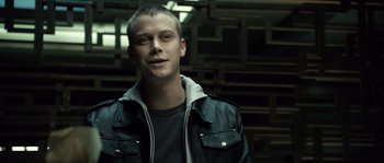 Movie still from “Daybreakers” (2009), directed by Michael Spierig – A man in a black leather jacket standing in front of a wall; Close Up shot, Low angle