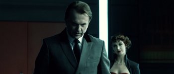 Movie still from “Daybreakers” (2009), directed by Michael Spierig – A man in a gray suit and a woman in a red dress; Close Up shot, Over the shoulder angle