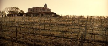 Movie still from “Daybreakers” (2009), directed by Michael Spierig – A large house sitting on top of a lush green hillside; Extreme Wide shot, Low angle