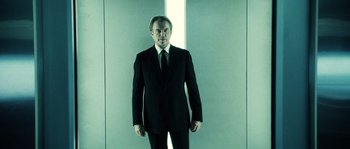 Movie still from “Daybreakers” (2009), directed by Michael Spierig – A man in a suit and tie standing in front of a wall; Medium shot, Low angle