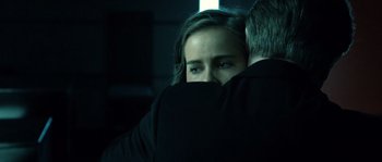Movie still from “Daybreakers” (2009), directed by Michael Spierig – A young woman hiding her face behind a man in a dark room; Close Up shot, Over the shoulder angle