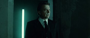 Movie still from “Daybreakers” (2009), directed by Michael Spierig – A man in a suit and tie standing next to a wall; Medium shot, Low angle