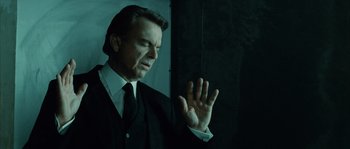 Movie still from “Daybreakers” (2009), directed by Michael Spierig – A man wearing a suit and tie holding his hand up to his face; Close Up shot, Low angle