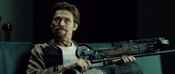 Movie still from “Daybreakers” (2009), directed by Michael Spierig – A man holding a gun while sitting on a couch; Medium shot, Low angle
