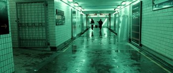Movie still from “Daybreakers” (2009), directed by Michael Spierig – Two people walking down a long hallway in a building; Wide shot, High angle