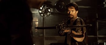 Movie still from “Daybreakers” (2009), directed by Michael Spierig – A man holding a gun while standing in a room; Medium shot, Over the shoulder angle