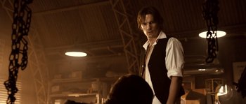 Movie still from “Daybreakers” (2009), directed by Michael Spierig – A man standing in a room with people around him; Medium shot, Over the shoulder angle
