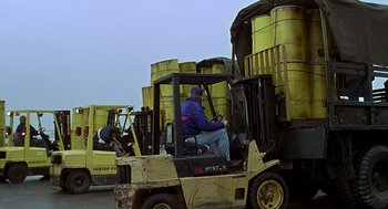 Movie still from “Daylight” (1996), directed by Rob Cohen – A man sitting on a fork lift in front of a truck; Wide shot, Low angle