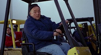 Movie still from “Daylight” (1996), directed by Rob Cohen – An older man sitting in the back of a forklift; Medium shot, High angle