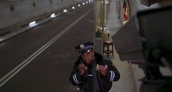 Movie still from “Daylight” (1996), directed by Rob Cohen – A man in a police uniform standing on a street; Medium shot, Low angle
