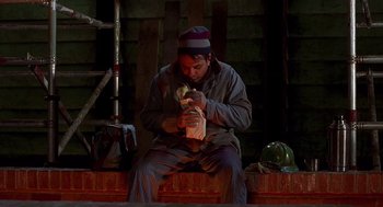 Movie still from “Daylight” (1996), directed by Rob Cohen – A man sitting on the ground with a bird in his hands; Medium shot, Low angle