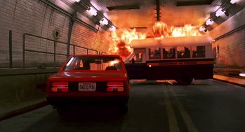 Movie still from “Daylight” (1996), directed by Rob Cohen – A red car is in a garage with a fire coming out of it; Wide shot, Low angle