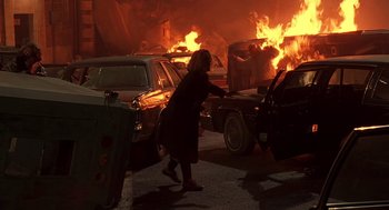 Movie still from “Daylight” (1996), directed by Rob Cohen – A woman walking through a parking lot near a fire; Wide shot, High angle