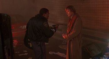 Movie still from “Daylight” (1996), directed by Rob Cohen – A police officer is pointing a gun at a man; Medium shot, Over the shoulder angle