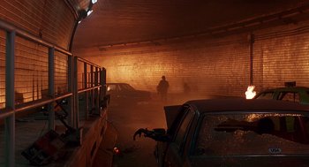 Movie still from “Daylight” (1996), directed by Rob Cohen – A man is standing in a parking garage with a car; Wide shot, High angle
