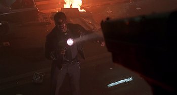 Movie still from “Daylight” (1996), directed by Rob Cohen – A man holding a flashlight in front of a fire; Medium shot, Low angle