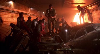 Movie still from “Daylight” (1996), directed by Rob Cohen – A group of people standing around a fire place; Wide shot, Low angle
