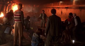 Movie still from “Daylight” (1996), directed by Rob Cohen – A group of people standing around in a room; Wide shot, Over the shoulder angle